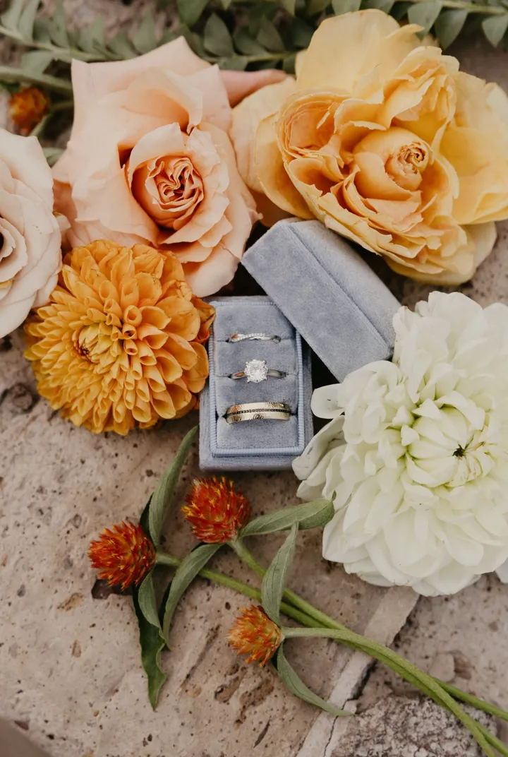Engagement ring in an open ring box surrounded by flowers